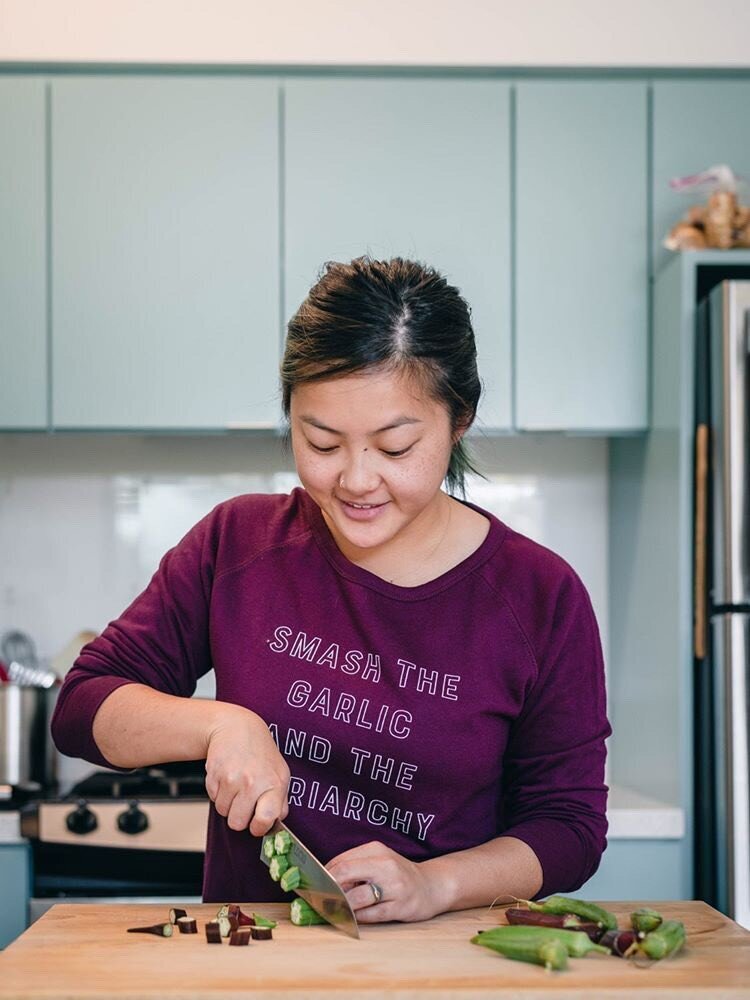 A woman wearing a maroon "Smash the Garlic and the Patriarchy" crewneck chops okra